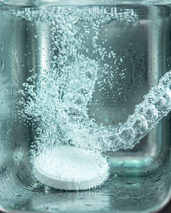 White tablet fizzing next to a retainer